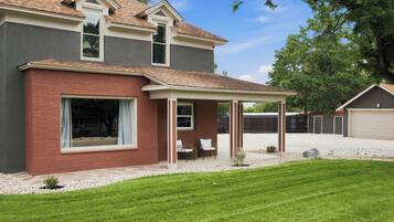 A two-story house with a covered patio, a garage, and a well-maintained lawn.