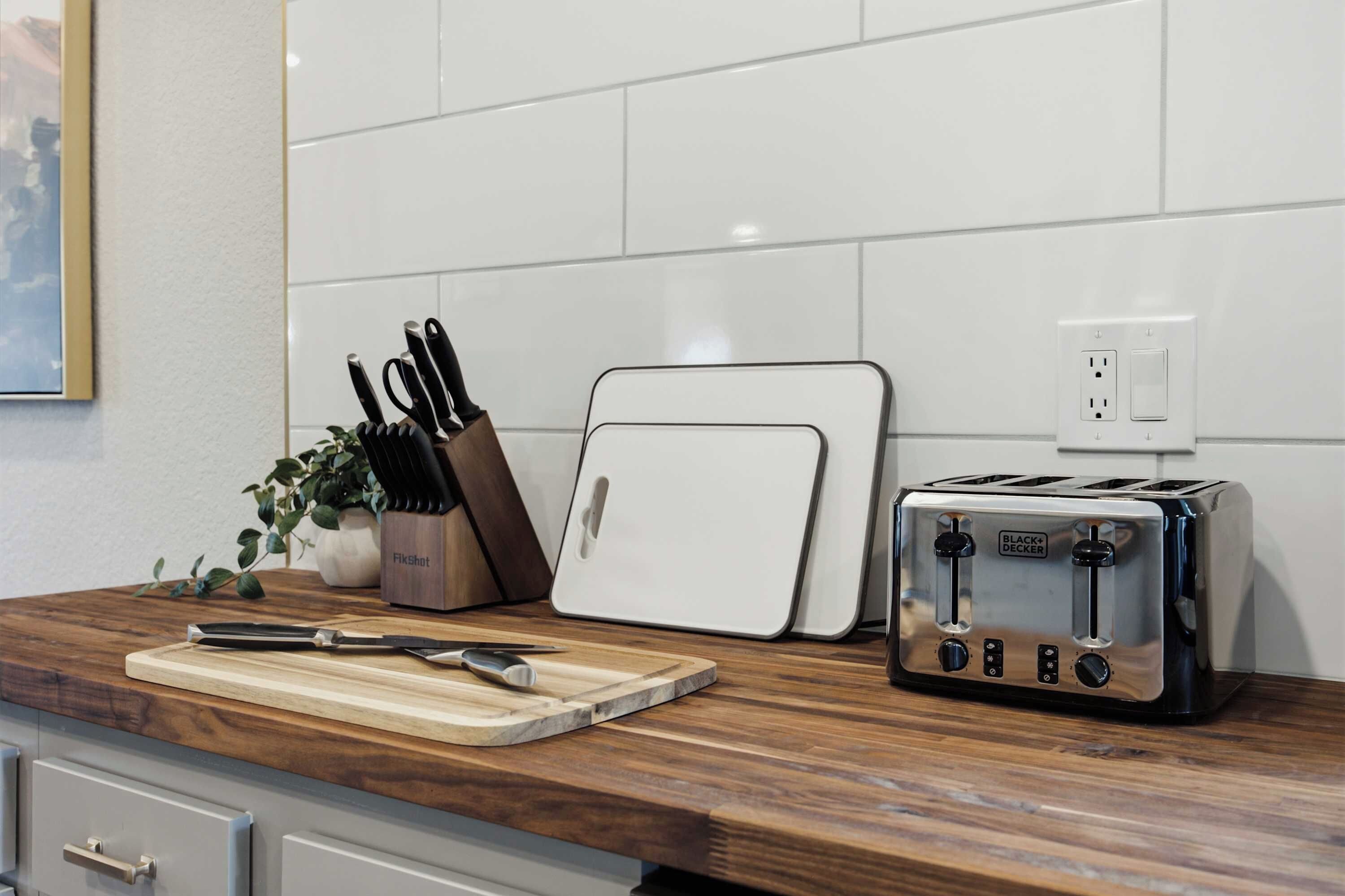 A kitchen counter with a toaster, a knife block, and a cutting board.