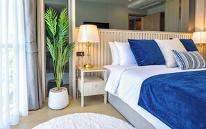 A hotel room with a bed, bedside table, lamp, and a potted plant. - OZON OASIS Apartment by TVC (Choeng Thale)