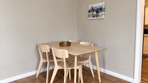 Ein Essbereich mit Holztisch und Stühlen, einer kleinen Pflanze auf dem Tisch und einem Bild an der Wand.