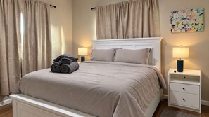 Ein Schlafzimmer mit einem Bett, einem Nachttisch, einer Lampe und einem Bild an der Wand.