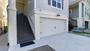 Ein Wohnhaus mit Garage, einer Treppe zum Eingang und einer Bank davor.