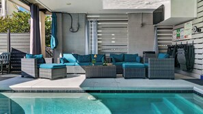 Ein Poolbereich mit Sitzgelegenheiten im Freien und Blick auf den Pool.