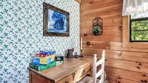 A wooden cabin interior with a desk, a framed picture of a bear, a potted plant, and a window with a view of trees. - Hibernation Station by Avantstay Hot Tub + Theater Room + Mtn Views Mins to Dollywood + Smokies (Sevierville)