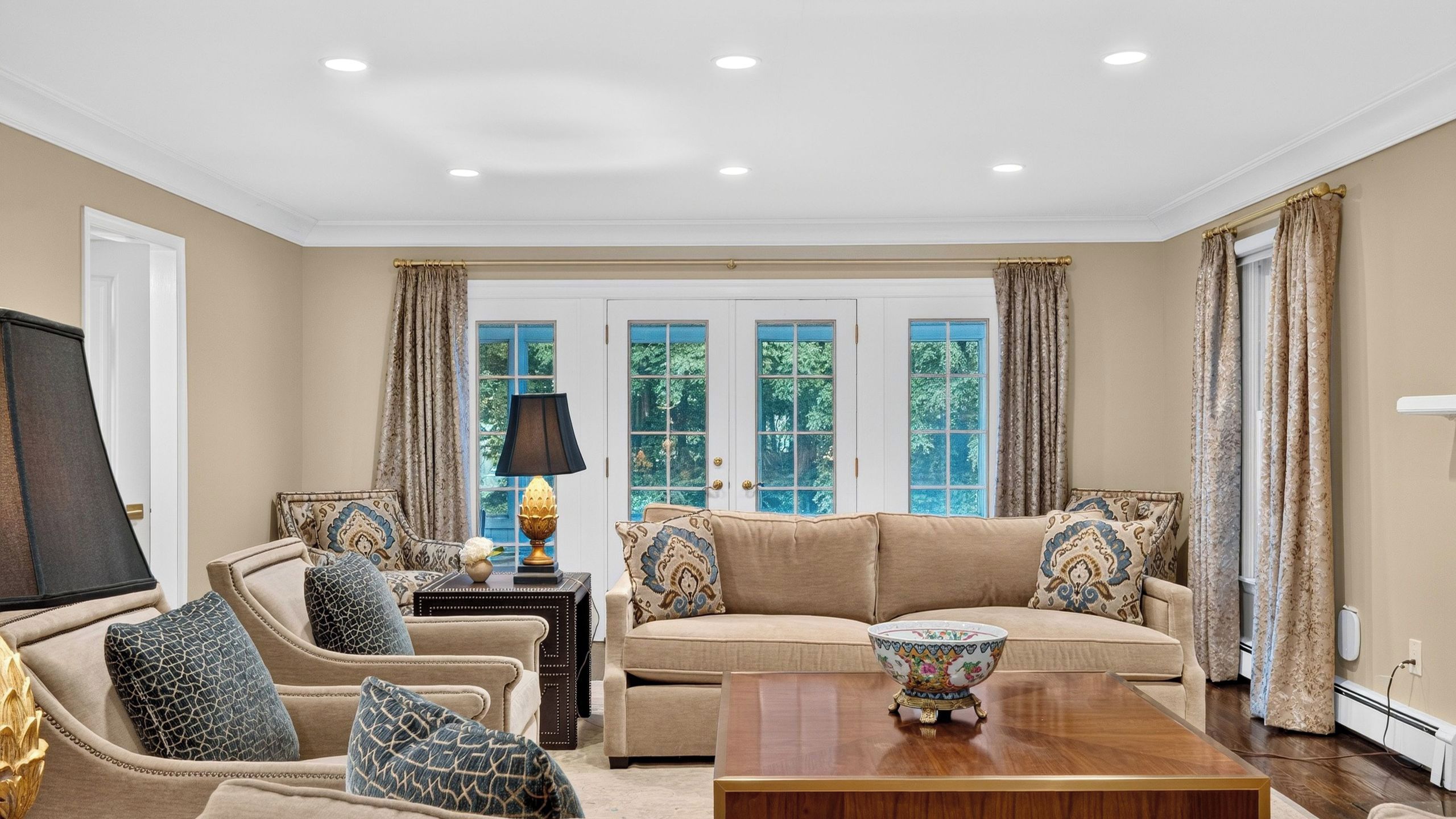 A spacious living room with a beige sofa set, a coffee table, and a decorative lamp.