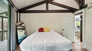 Ein Schlafzimmer mit einem großen Bett, einem Spiegel und einer Tür zu einem weiteren Raum.