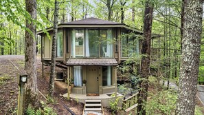 Eine zweistöckige Holzhütte mit Balkon, umgeben von Bäumen.