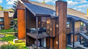 Ein modernes, mehrstöckiges Gebäude mit Balkon, großen Fenstern und einem gepflegten Rasen.