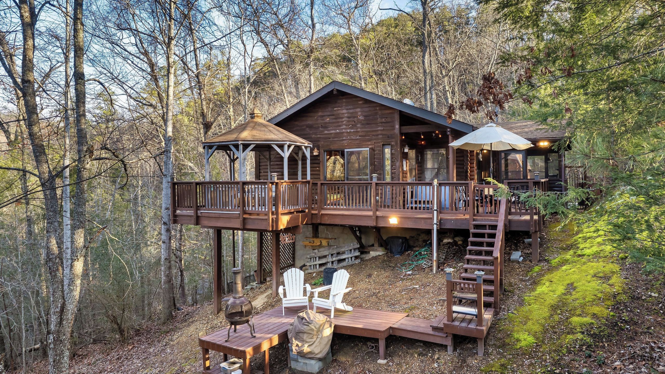 A cabin with a deck, outdoor seating, and a chimney.