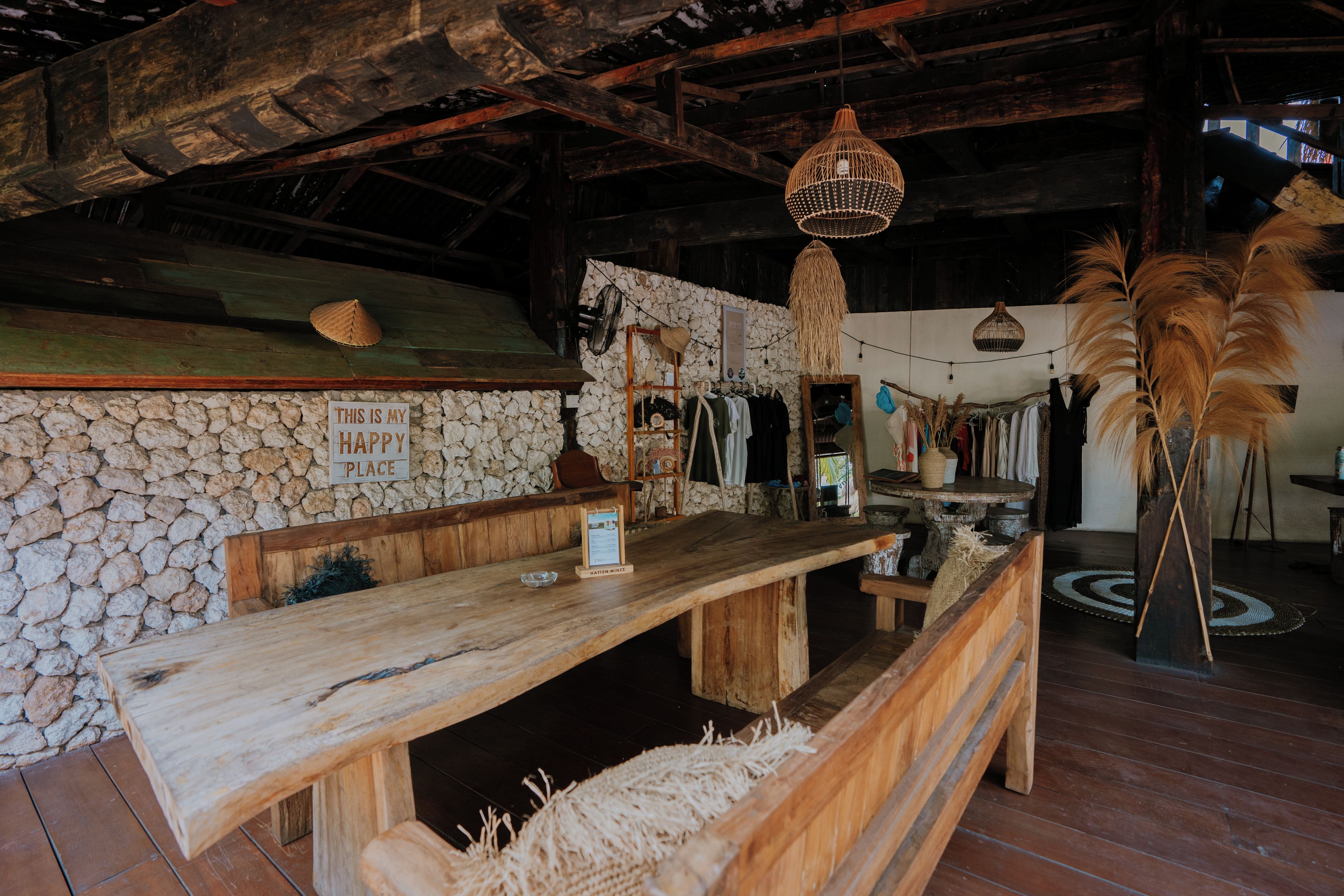 Un interior rústico con pared de piedra, banco de madera y un letrero que dice 'THIS IS MY HAPPY PLACE'.