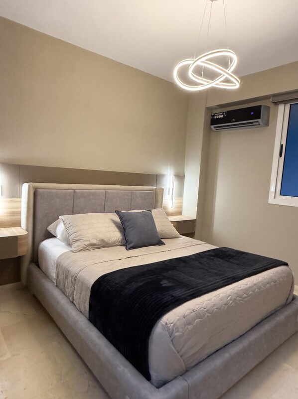 A modern bedroom with a bed, bedside tables, and a ceiling light fixture.