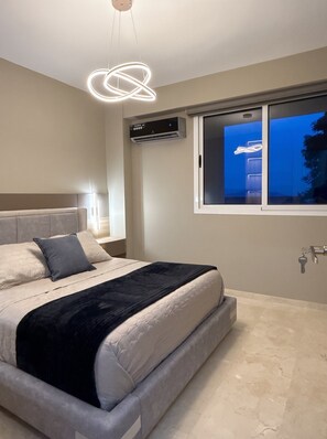 Quarto com cama, mesa de cabeceira, janela com vista e luminária moderna.