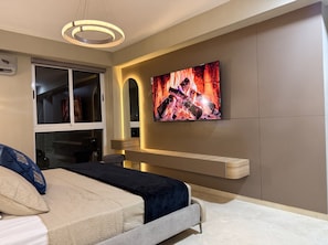 A modern bedroom with a bed, a TV mounted on the wall, and a built-in bench.
