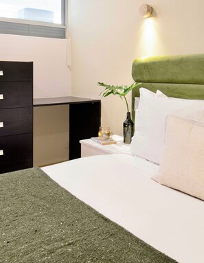 A neatly arranged hotel room with a bed, bedside table, and a dresser. - Beautiful apartment in the heart of Polanco (Mexico City)