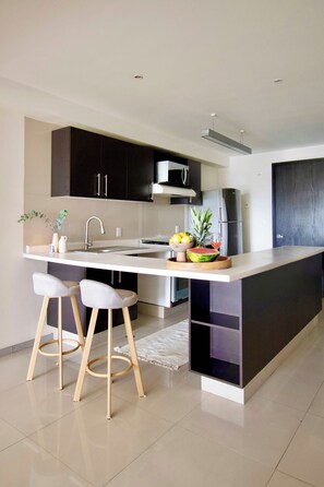 A modern kitchen with a central island, stainless steel appliances, and a minimalist design. - Beautiful apartment in the heart of Polanco (Mexico City)