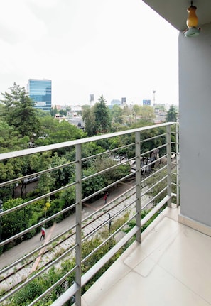A balcony with a view of a railway track and greenery, a building with reflective windows, and a clear sky. - Beautiful apartment in the heart of Polanco (Mexico City)