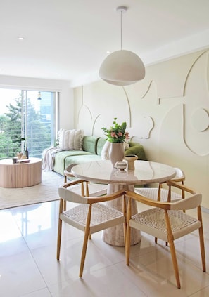 A modern living room with a round table, wicker chairs, a green sofa, and a vase with flowers. - Beautiful apartment in the heart of Polanco (Mexico City)