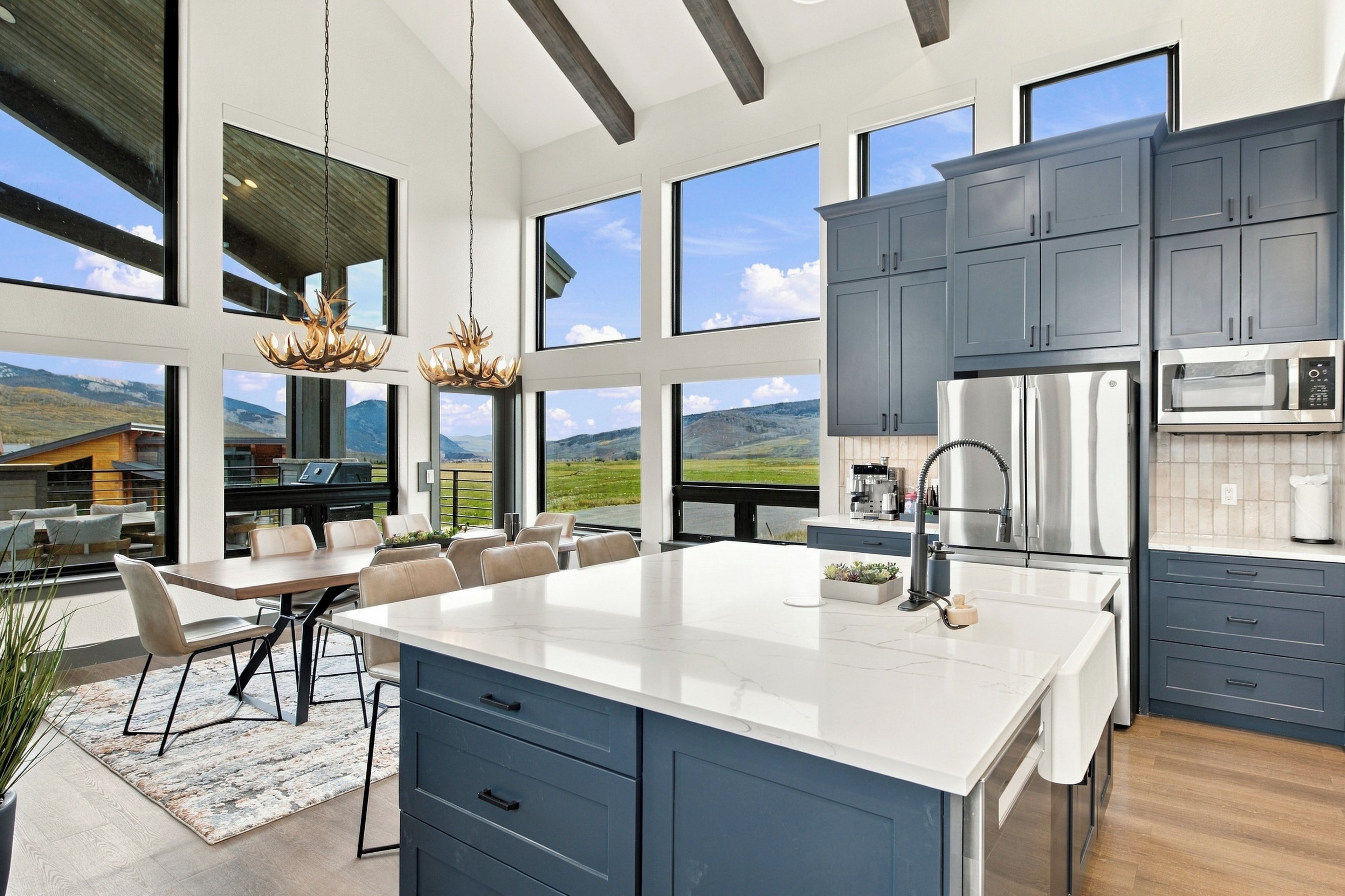 A modern kitchen with a large island, stainless steel appliances, and a view of the mountains.