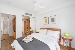 A hotel room with a bed, bedside tables, a ceiling fan, a wardrobe, and a bathroom. - Funky Teneriffe - 2bed-2bath-balcony-1car (Brisbane)