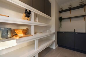 A modern kitchen with white cabinetry, a wooden bowl on the counter, and a knife block on the shelf. - Sunset Cove - Bribie Island Waterfront Retreat (Bribie Island Region)