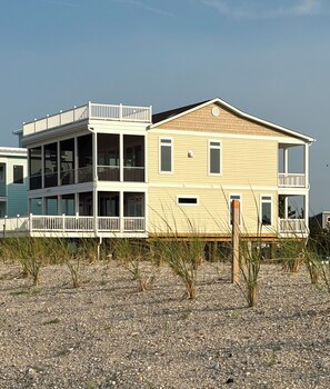 A two-story beachfront house with a balcony and a covered porch. -  New luxurious beachfront home with saltwater pool (Milton)