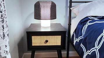 A bedroom with a bed, a nightstand with a lamp, and a patterned curtain.