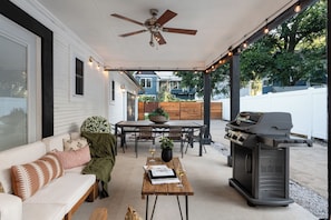 A covered patio with a ceiling fan, a barbecue grill, a dining table with chairs, and a sofa with cushions. - Luxe 4BR/3BA • Heated Pool + Gym, 5 Min Downtown (Austin)