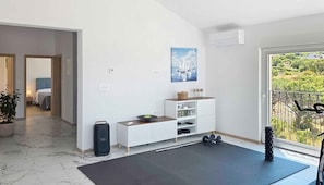 A modern living room with a workout area, including a yoga mat, dumbbells, and a stationary bike. - Holiday home with swimming pool (Punat)