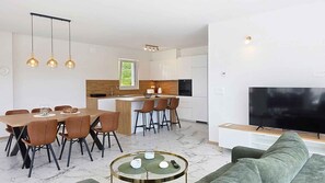A modern kitchen with a dining area, a living room with a sofa and a TV, and a marble floor. - Holiday home with swimming pool (Punat)