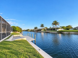 A waterfront property with a modern building, a grassy area, and a calm water body. - Perfect 4-bedroom house with AC in charming Cape Coral (Cape Coral)