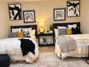 A hotel room with two beds, a bedside table with a lamp, a mirror, and framed artwork on the wall. - Perfect 4-bedroom house with AC in charming Cape Coral (Cape Coral)