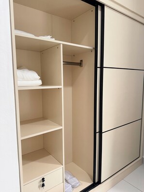 Ein Schrank mit mehreren Einlegeböden, einer Kleiderstange und einer Schiebetür.