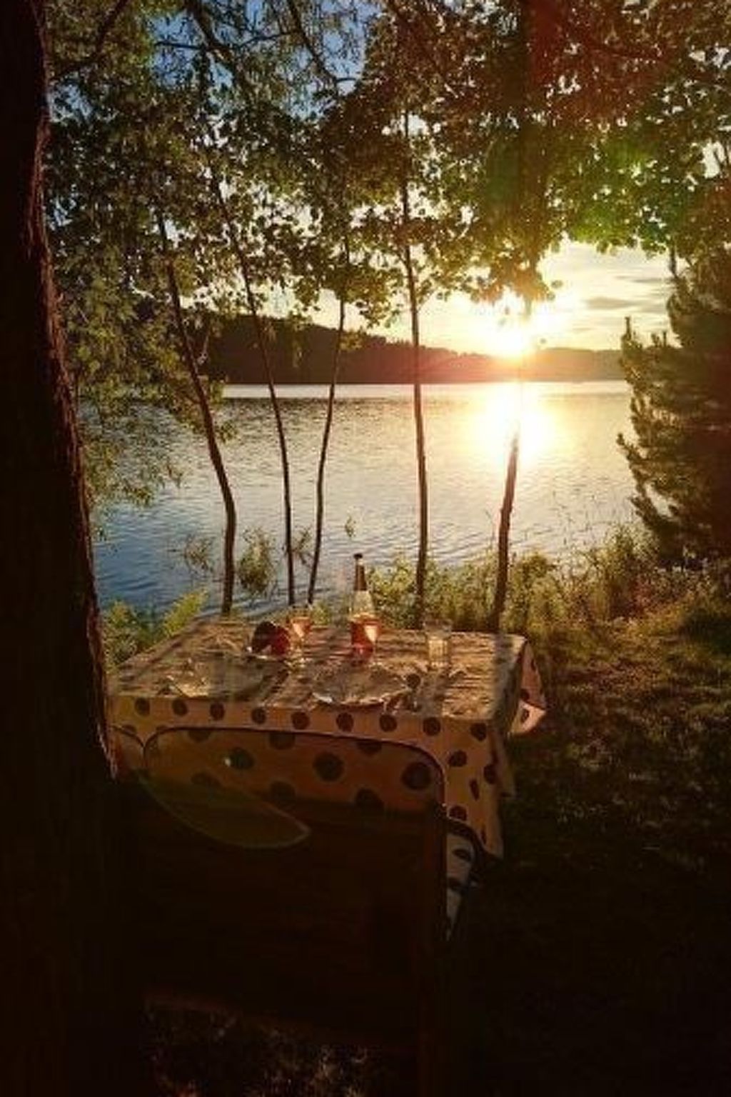 A table set outdoors with a view of a lake and sunset.