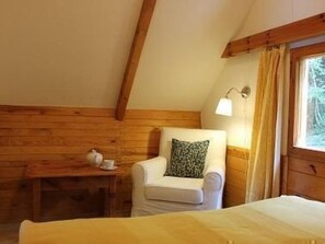 A room with a bed, a chair, a small table with a cup, and a lamp. - Haus am See by Interhome (Frymburk)