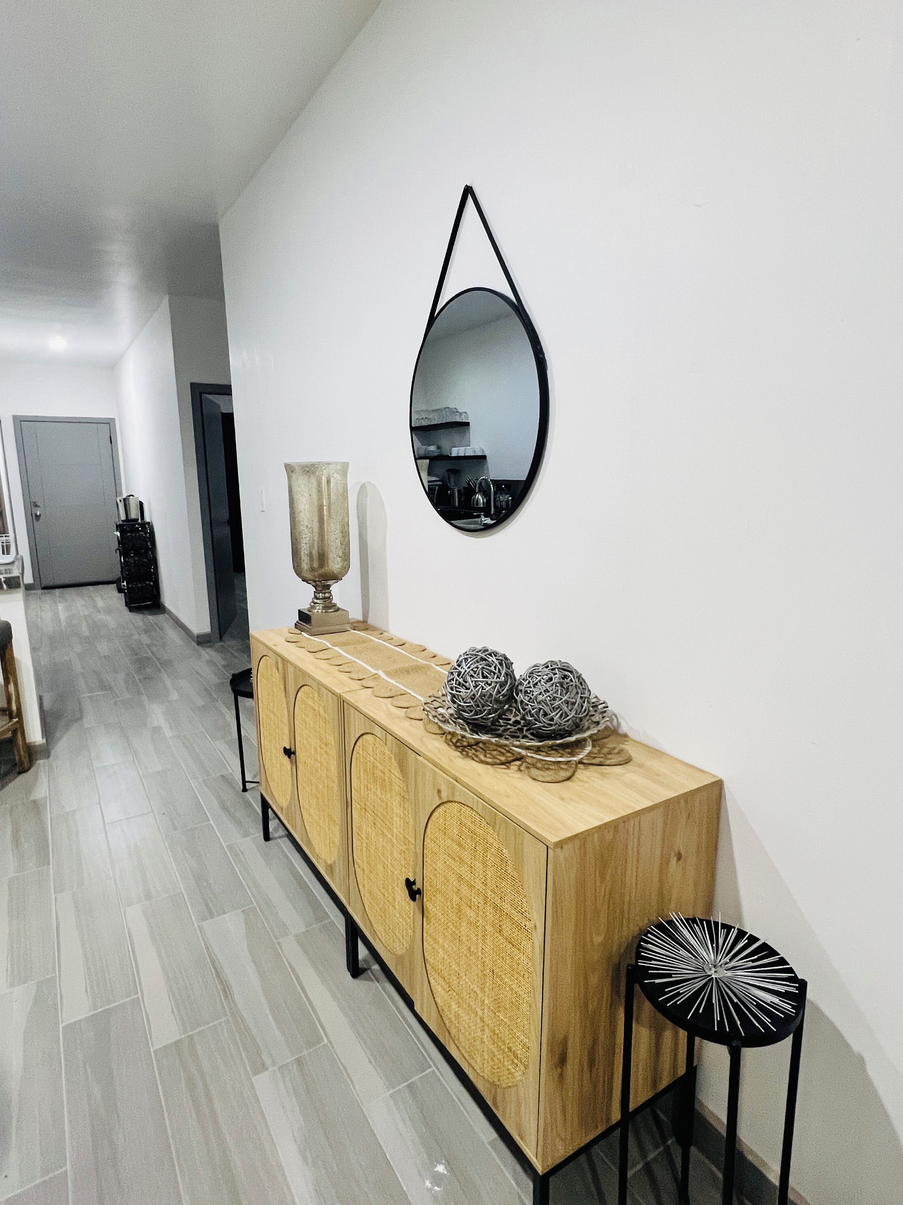 A modern interior with a wooden cabinet, a mirror, and a patterned floor.