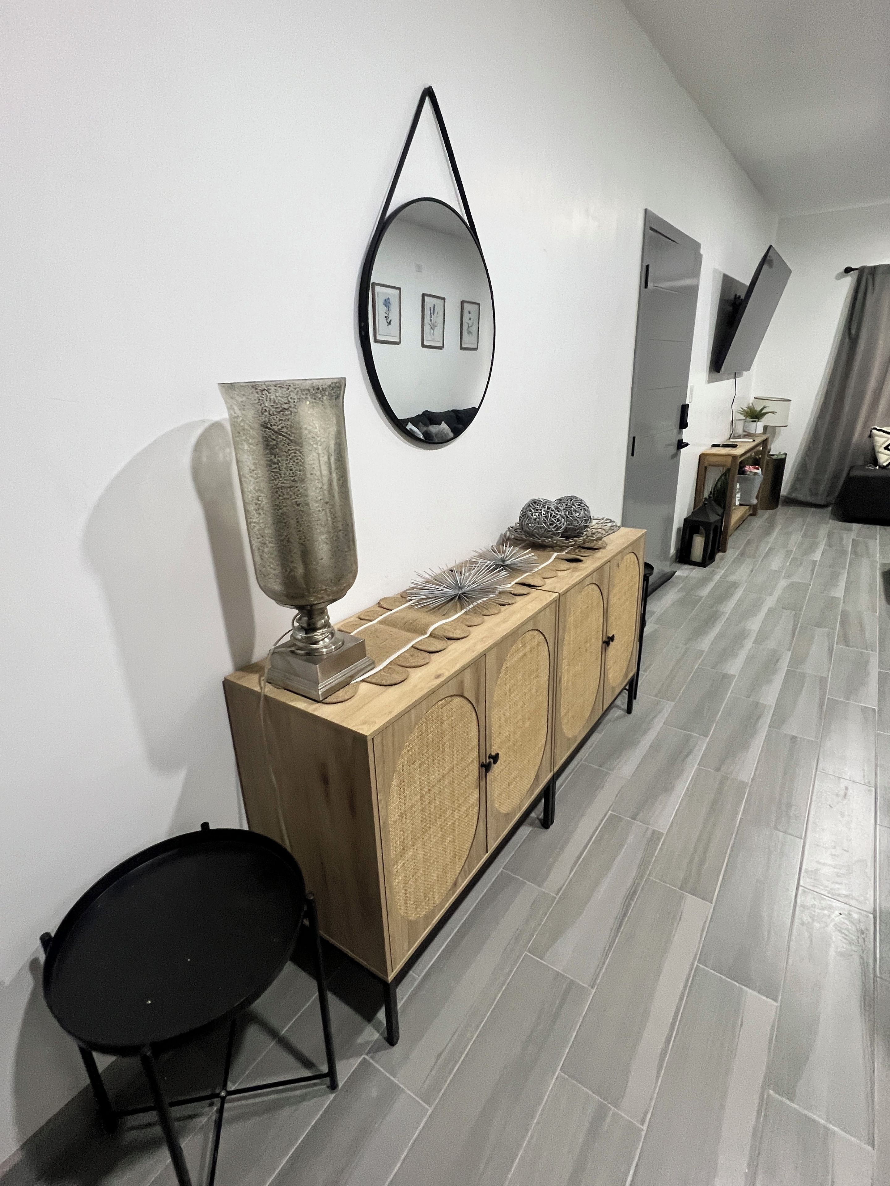 A modern living room with a wooden cabinet, a large mirror, and a black chair.