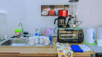 Een keuken met een spoelbak, koffiezetapparaat, blender, broodrooster en waterkoker.