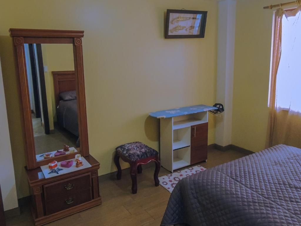 Une chambre à coucher comprenant un lit, une commode, un miroir, un petit tabouret et un bureau.