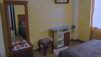Une chambre à coucher comprenant un lit, une commode, un miroir, un petit tabouret et un bureau.