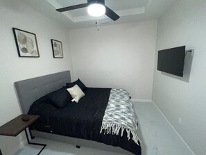 A bedroom with a bed, a nightstand, a ceiling fan, and two framed pictures on the wall. - Apartment in Weslaco, TX. 3BR / 2 BA (Weslaco)