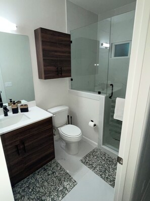 A bathroom with a toilet, sink, and shower area. - Apartment in Weslaco, TX. 3BR / 2 BA (Weslaco)