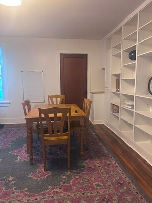 A room with a wooden dining table, chairs, a patterned rug, a whiteboard, and a bookshelf. - Comfortable, Pet Friendly, Historic Home in Huntsville (Huntsville)