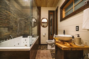 Een moderne badkamer met een douchecabine van glas, een houten wastafelmeubel, een wastafel en een toilet.