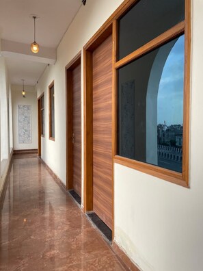 Un pasillo con puertas de madera y ventanas grandes.