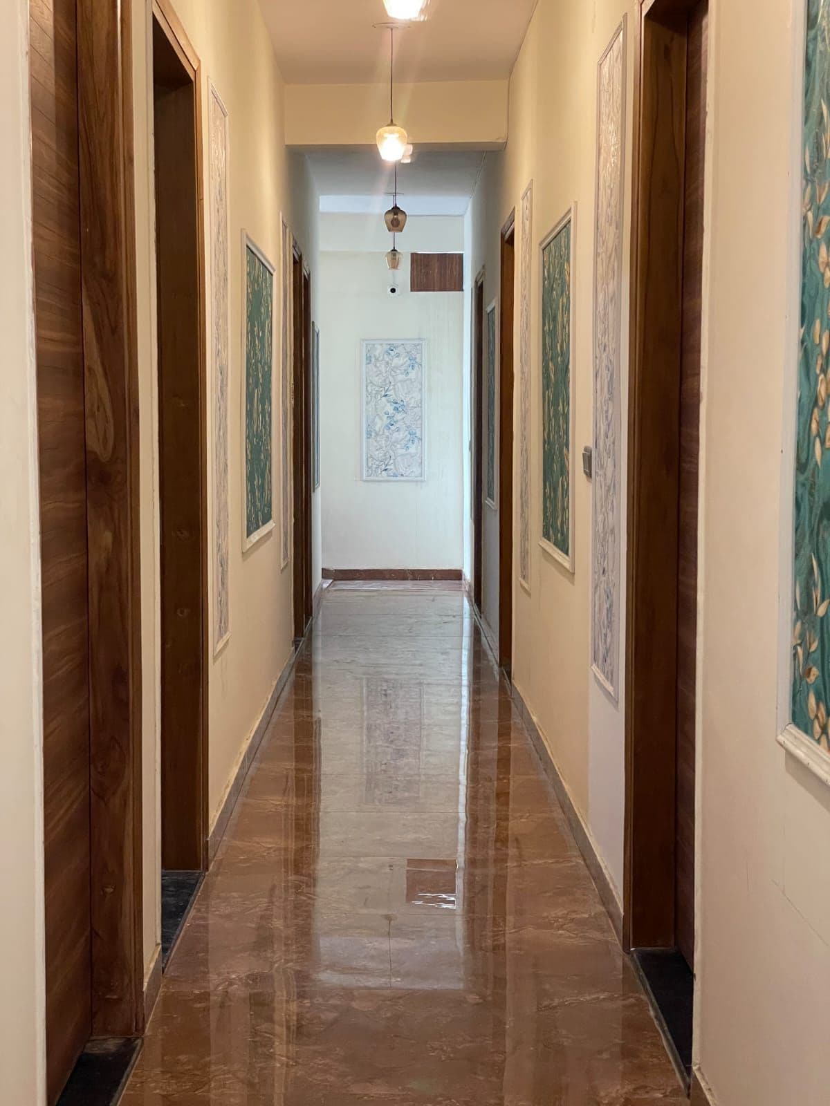 Un pasillo con puertas de madera, obras de arte enmarcadas en las paredes y un suelo pulido.