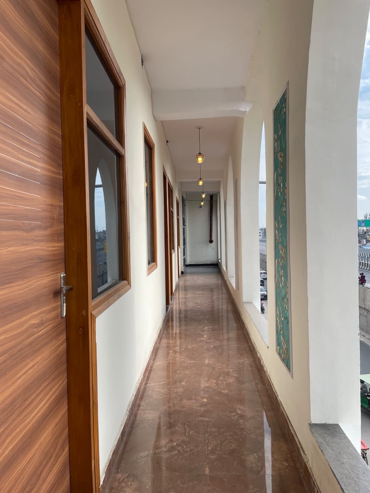 A corridor with wooden doors, large windows, and a ceiling light fixture.