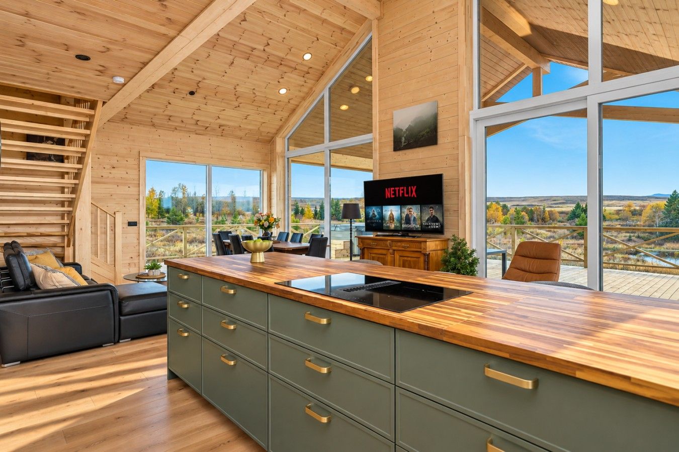 Een moderne keuken met een groot eiland, houten kastjes en uitzicht op de omgeving.