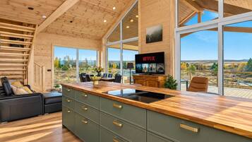 Een moderne keuken met een groot eiland, houten kastjes en uitzicht op de omgeving.