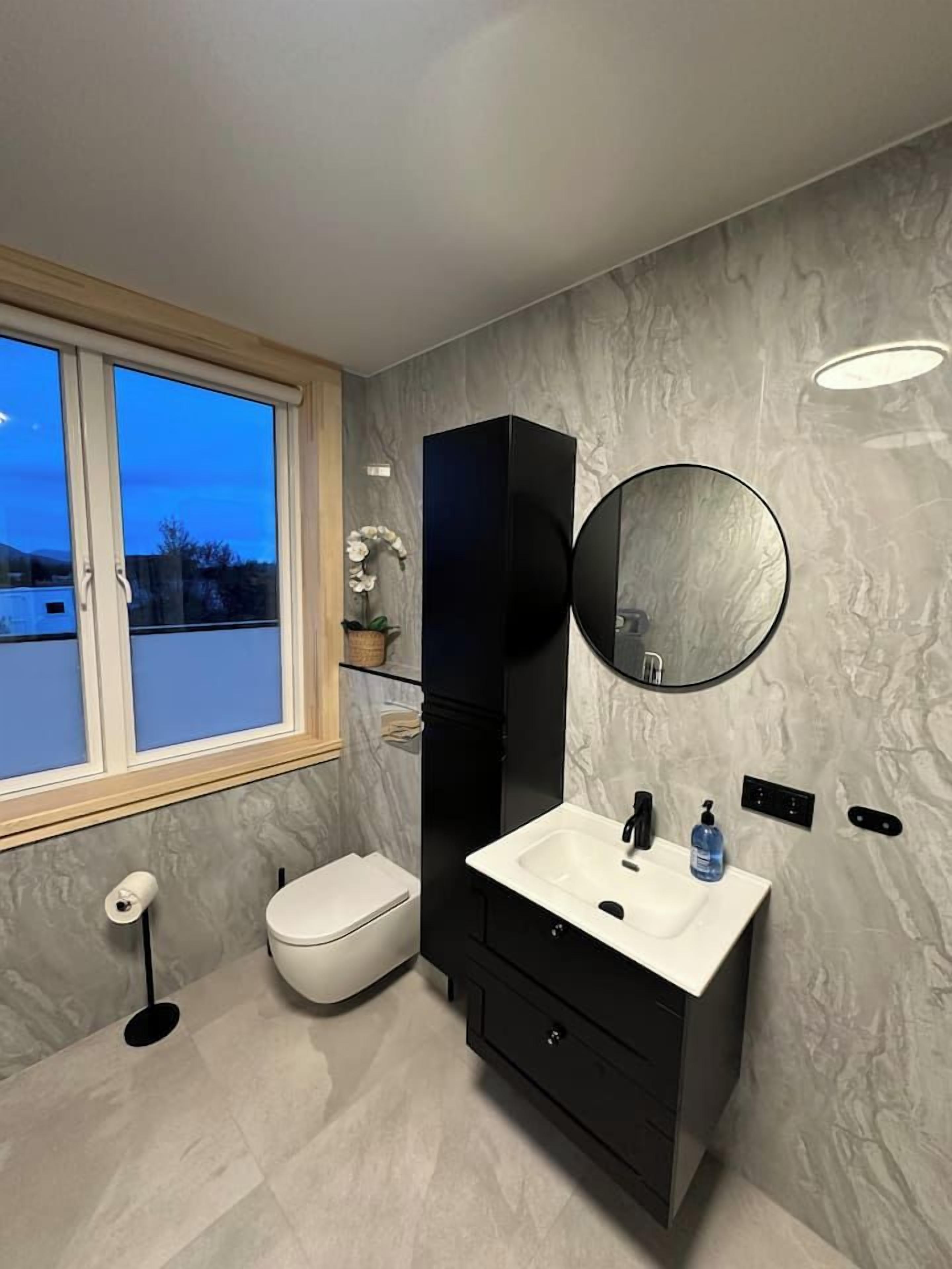Ein modernes Badezimmer mit Toilette, Waschbecken und Spiegel.