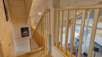 A wooden staircase with a railing leading to an upper level.